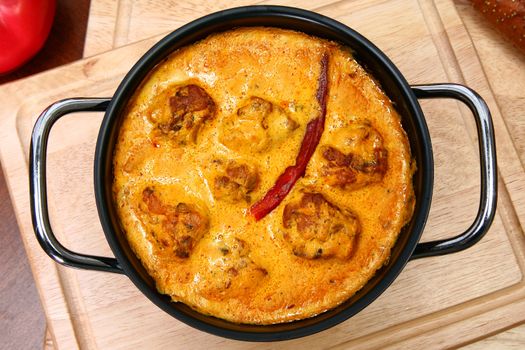 Indaian Gram Flour Dumplings in Yogurt Curry Sauce in Pot on Table