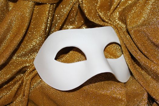 White carnival mask on golden glitters