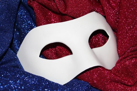 White carnival mask on red and blue glitters