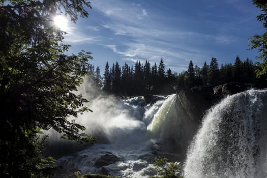 Beautiful mountain waterfall in sunny day with blue sky 