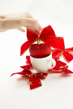 Cup with a heart in it tied with a ribbon. Other ribbons on the background are spread around.