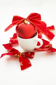 Cup with a heart in it tied with a ribbon. Other ribbons on the background are spread around.