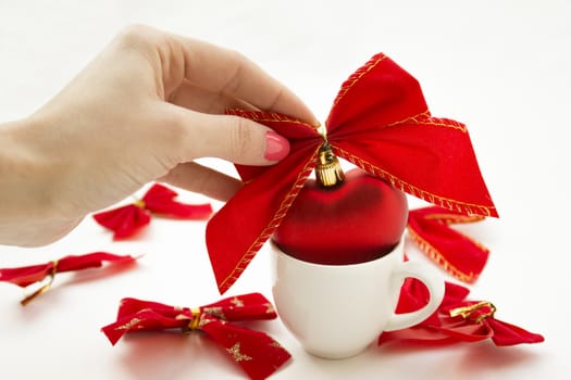 Cup with a heart in it tied with a ribbon. Other ribbons on the background are spread around.