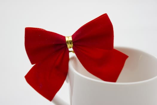 Isolated white cup with red and gold ribbon on top. 