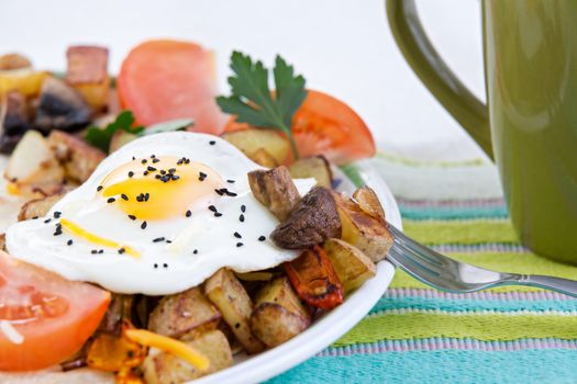 Tasty meal of a farm fresh fried egg with a rich yellow yolk served sunny side up with vegetables including savoury mushrooms, potato and tomato garnished with parsley on a colourful placemat