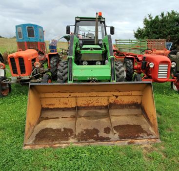 Close up on ancient tractor shover next to other in the countryside