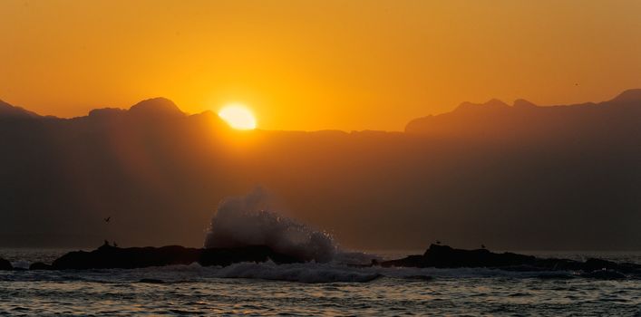 Big wave front with bubbles and splashes at sunset