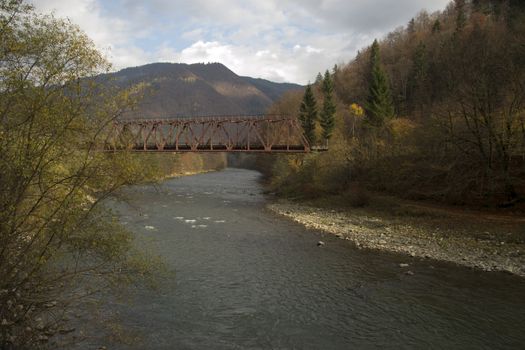 Metal bridge over the river among the mountains