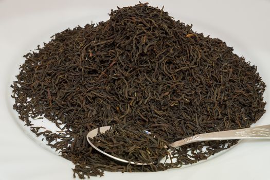 Black tea with a spoon on a white background.