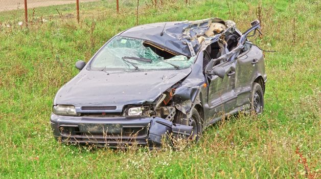 Hard crashed car in a field.