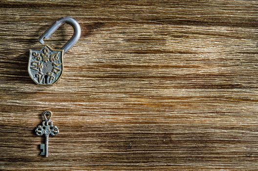 Open vintage padlock and old key on a wooden textured table