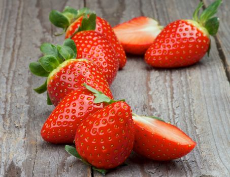 Arrangement of Fresh Ripe Strawberries with Stems Full Body and Halves isolated on Rustic Wooden background