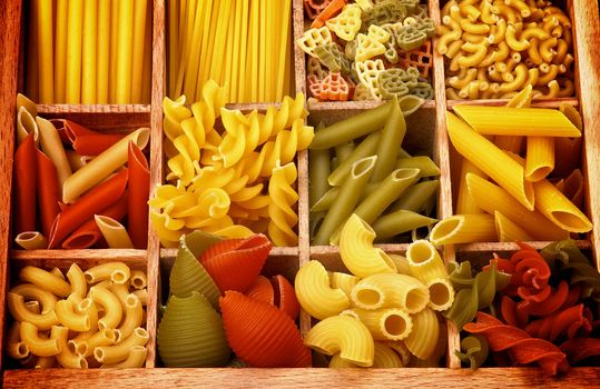 Various Raw Dry Colorful Pasta with Pasta Shells and Fusillini closeup in Wooden Sections