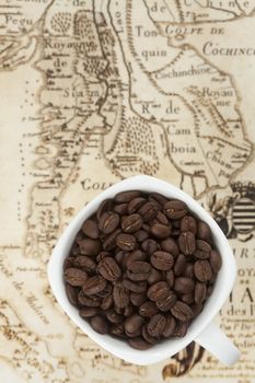 Cup full of coffee beans on the old map