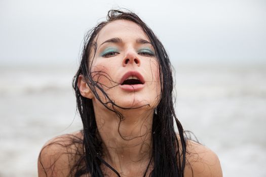 Portrait if frozen wet young woman on cold sea background