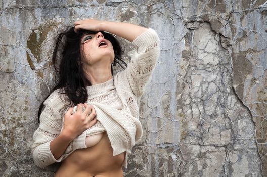Naked woman against old concrete wall background