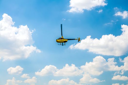 Yellow tourist Helicopter in the blue cloudy sky