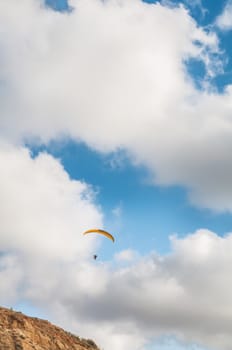 Flying paraglider on the cloudy sky background