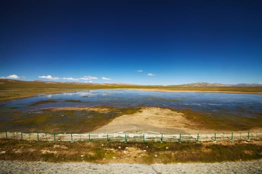 A view of clear blue lake with mountain landscape in the background at Tibetan Plateau