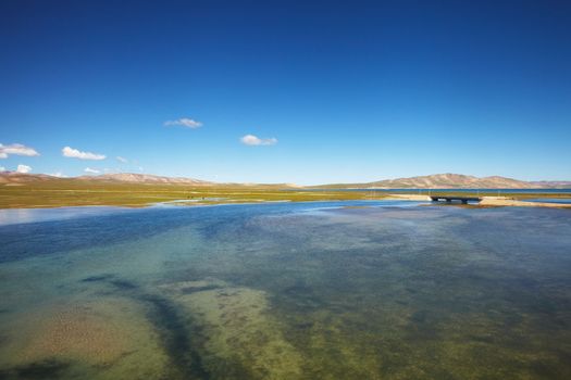 A view of clear blue lake with mountain landscape in the background at Tibetan Plateau