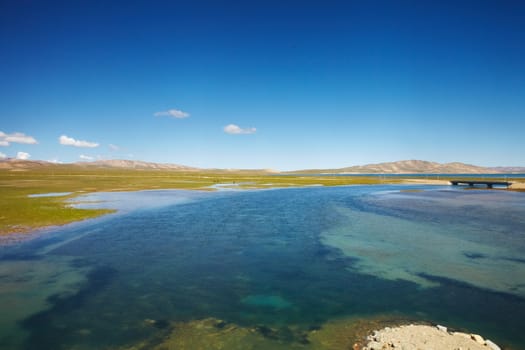 A view of clear blue lake with mountain landscape in the background at Tibetan Plateau