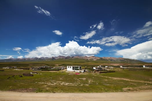 A Tibetan rural village in the outskirts.  Mountain landscape with cloudy sky