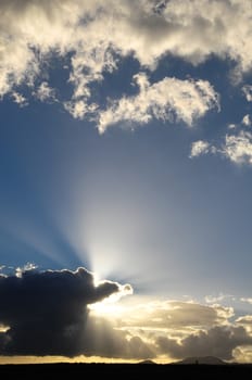 Sun Rays and Clouds over a Blue Sky at Sunset