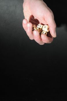 One Left Male Hand Playing Dice on a Black Background