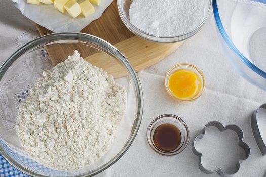 Baking ingredients including flour, egg yolk and vanilla extract, with cookie cutter.