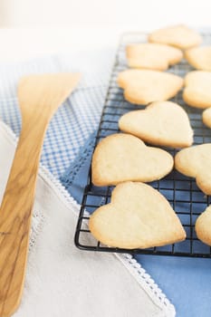 Fresh baked heart shaped cookies on cooling rack.