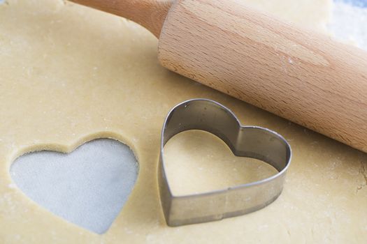 Dough rolled out with heart shape cut out, and heart shaped cookie cutter
