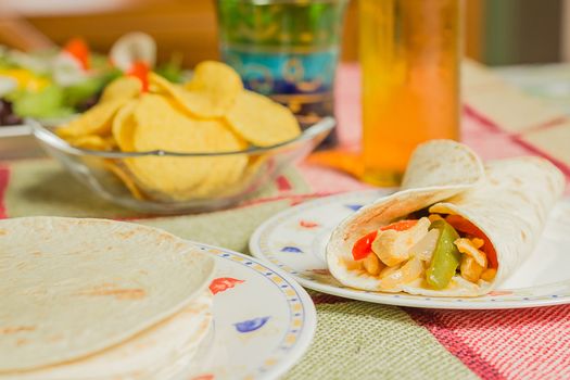 Traditional mexican food in a table, with bowl of nachos, spicy sauce, chicken fajita, tortillas and fresh salad