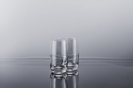 Two transparent empty tall glasses on a gradient simple background