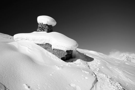 Winter landscape with weird rocky boulders covered by thick windswept snow.