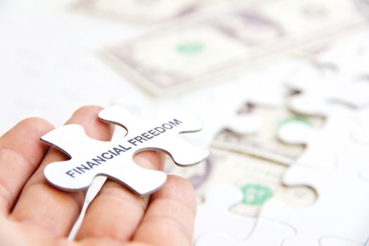 hand holding a puzzle piece, financial freedom concept