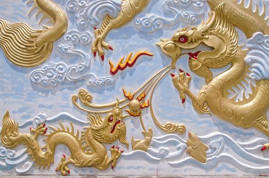 gold chinese dragon statue at teh wall of chinese temple in Thailand