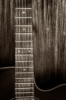 Detail of acoustic guitar in vintage style on wood texture background