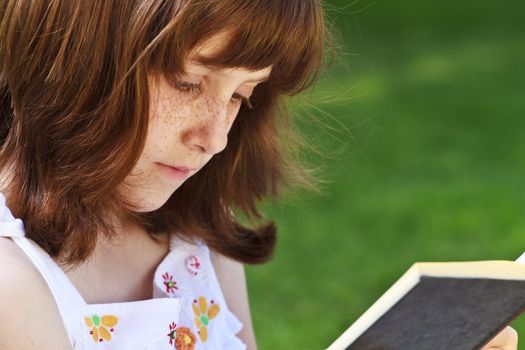 Young beautiful girl reading a book outdoor