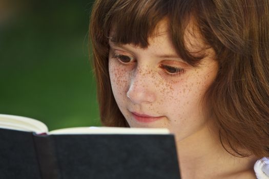 Literature.Young beautiful girl reading a book outdoor