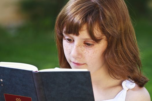 Literature.Young beautiful girl reading a book outdoor