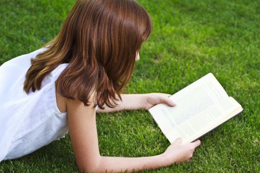 One.Young beautiful girl reading a book outdoor