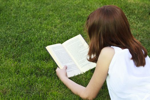 Student.Young beautiful girl reading a book outdoor