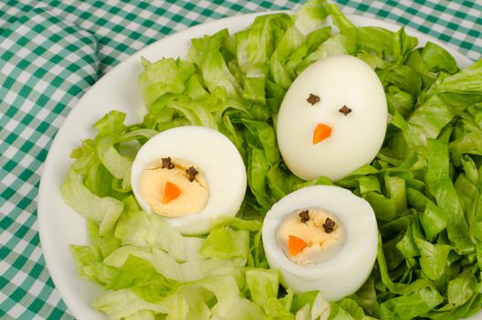 A salad served with decorated eggs, a kid meal