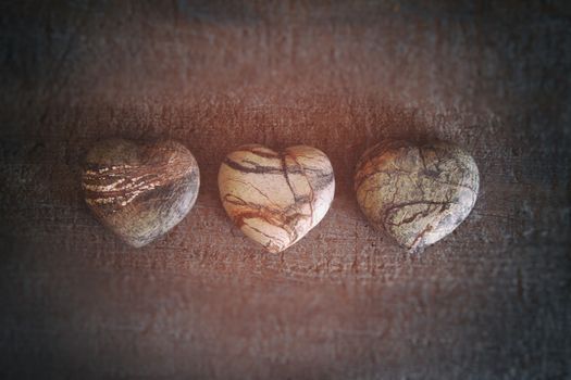 Three stone hearts on wood background