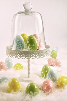 Cake stand with easter eggs and white feathers