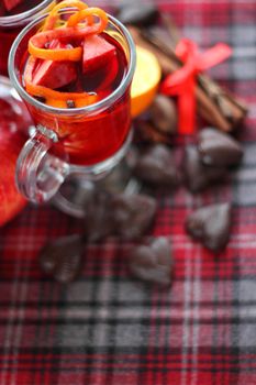 Hot red mulled wine with fruits and cinnamon on checkered tablecloth