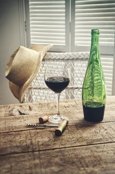 Glass of red wine standing on an old table with straw hat