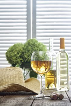 Glass of wine standing on an old table with straw hat