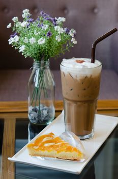 piece of  peach tart on dish with ice coffee