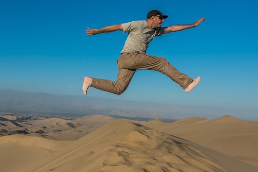 man jumping in the desert in the peruvian coast at Ica Peru